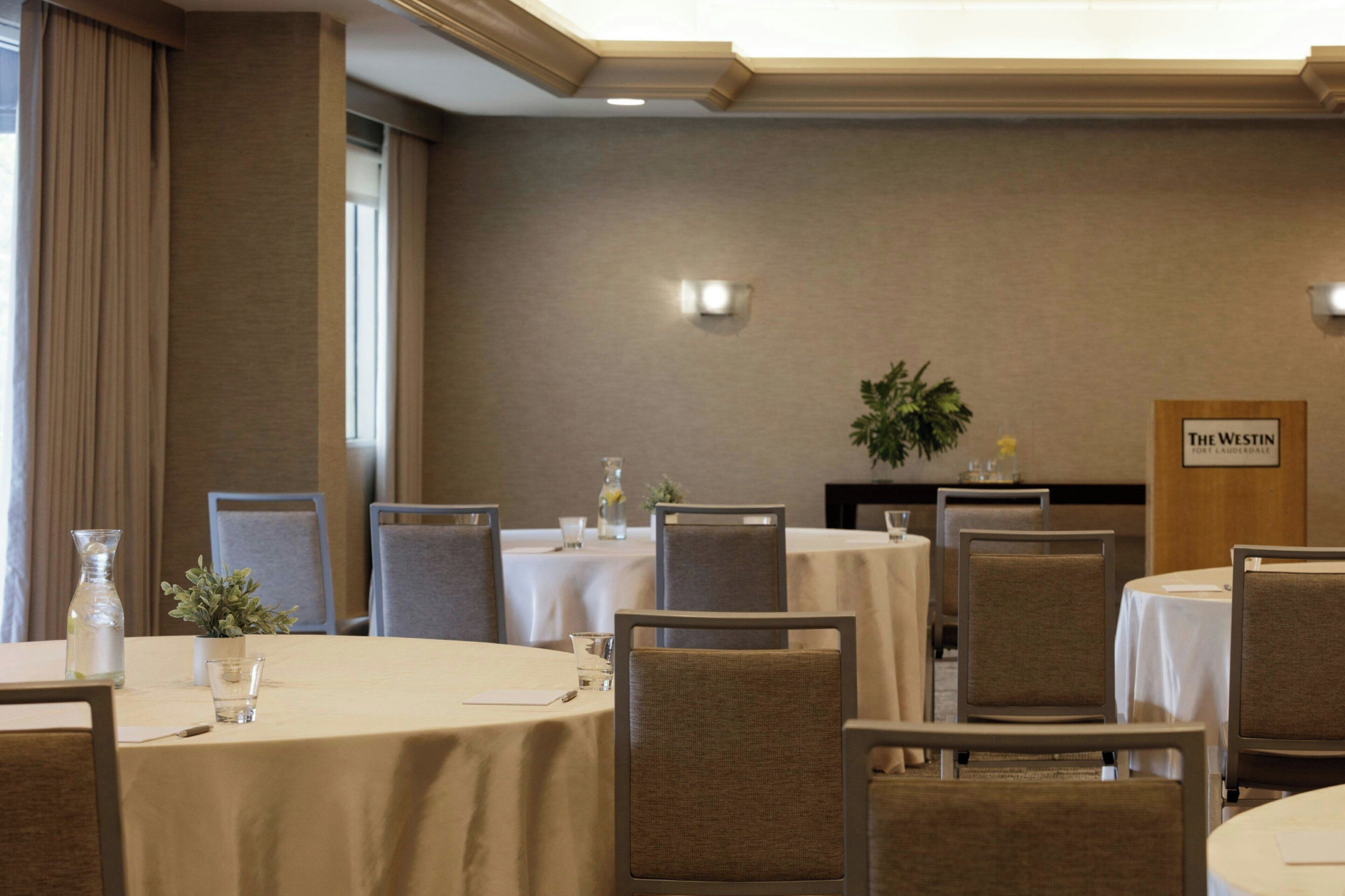 En hotellrestaurang med runda bord, stolar och en skylt som visar namnet ”The Westin”.