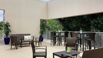 Un espace extérieur aménagé en terrasse, avec des meubles en osier, des plantes en pot et une vue sur la verdure environnante.