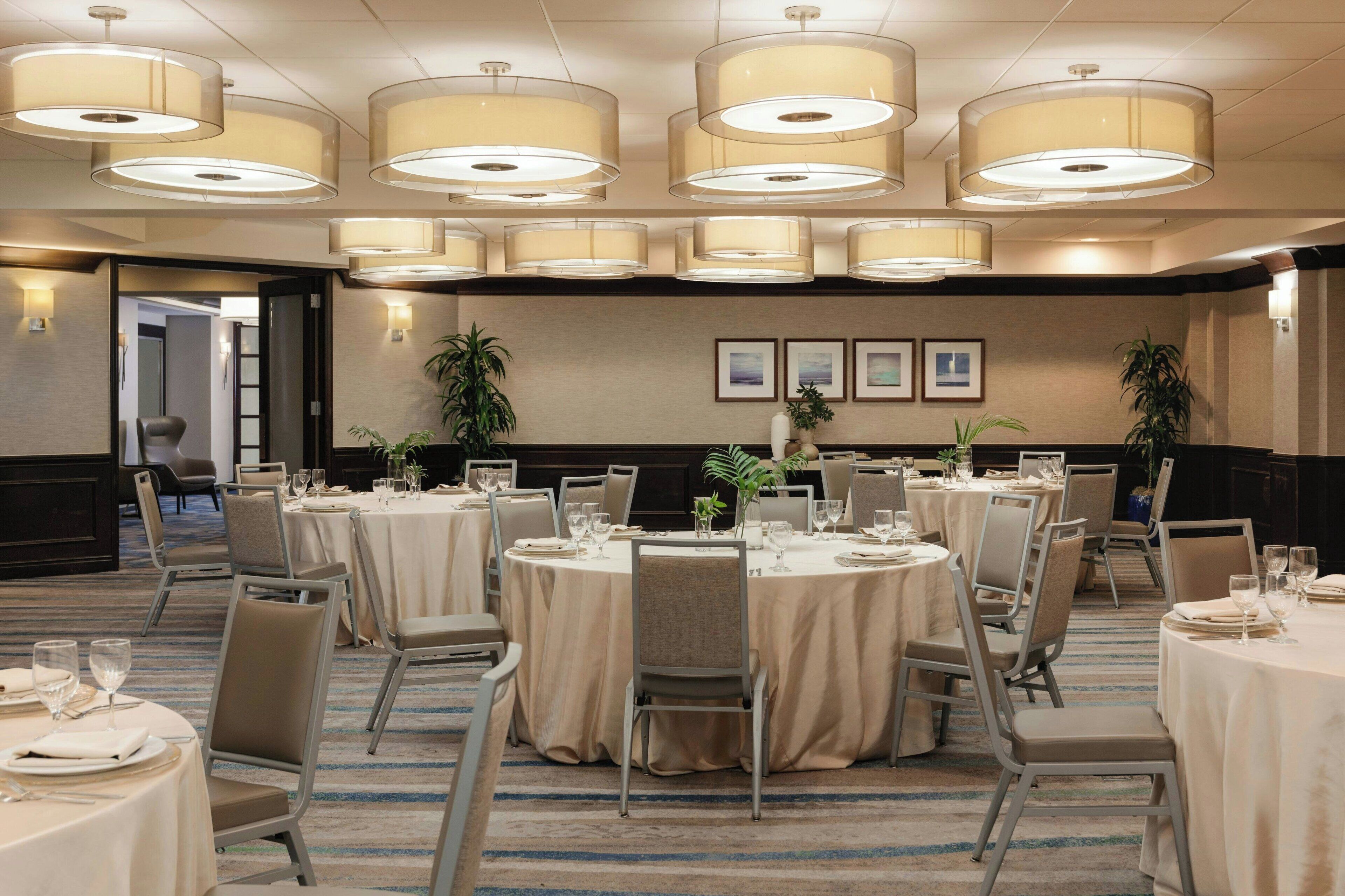 A conference room with round tables, chairs, and large ceiling lamps.