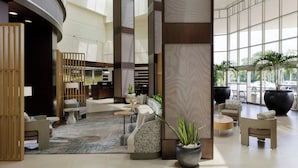 A spacious lobby with a curved reception desk, seating areas, and large windows offering views of the outdoors.