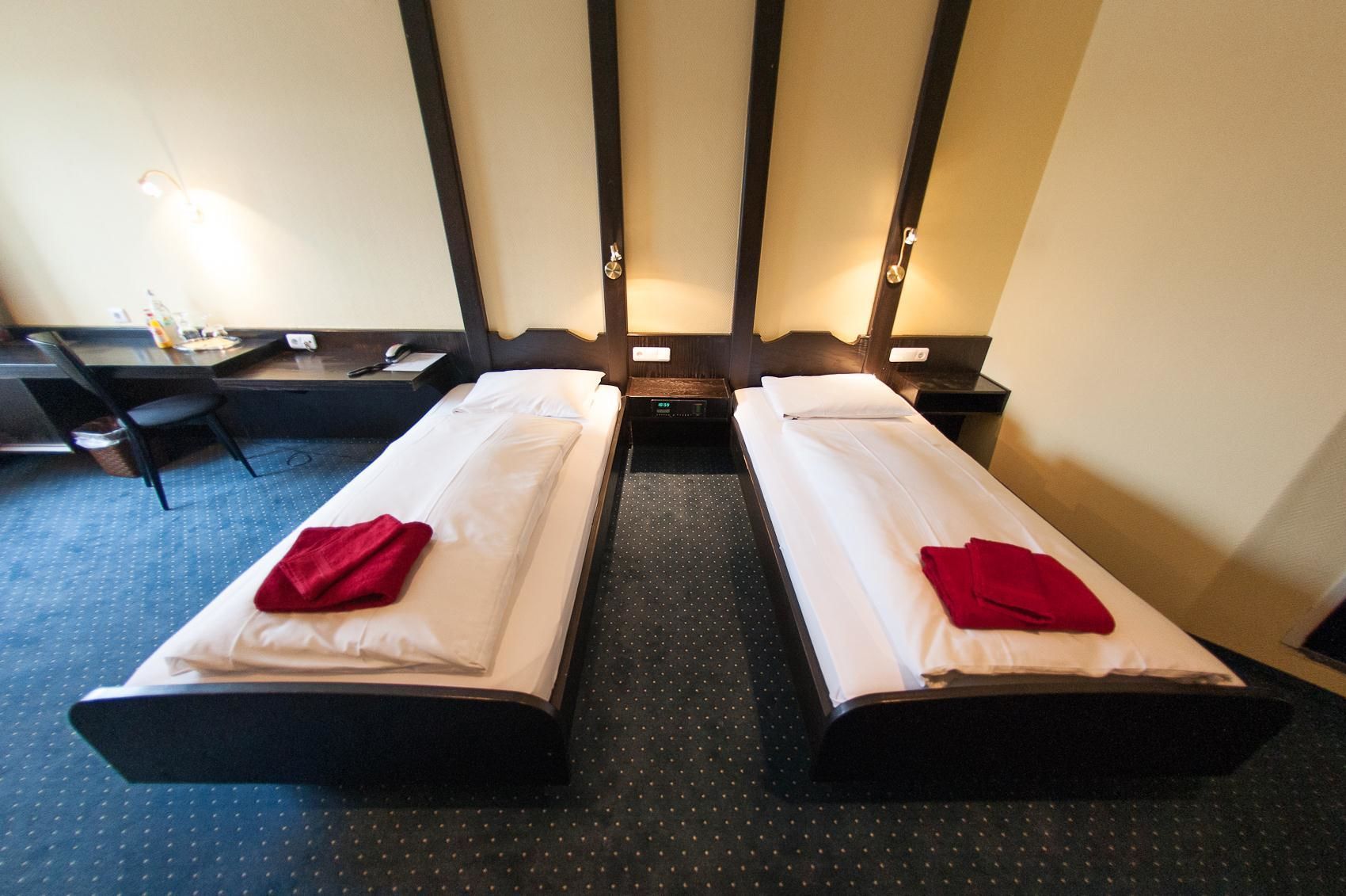 Une chambre d’hôtel avec deux lits simples, un bureau et une chaise.