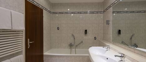 A modern bathroom with a bathtub, two sinks, and a large mirror.