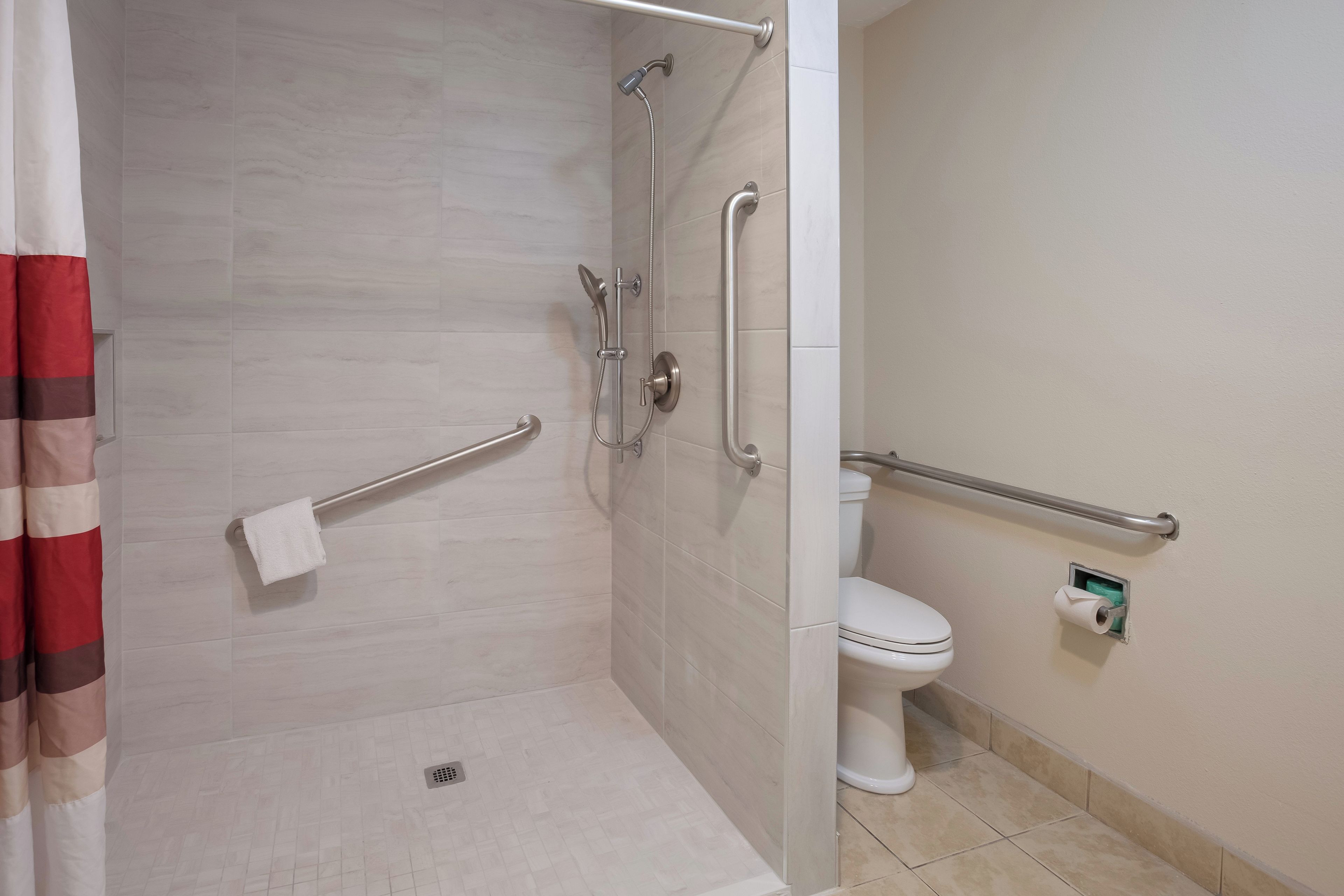 Une salle de bain équipée d’une douche, de toilettes et de barres d’appui.