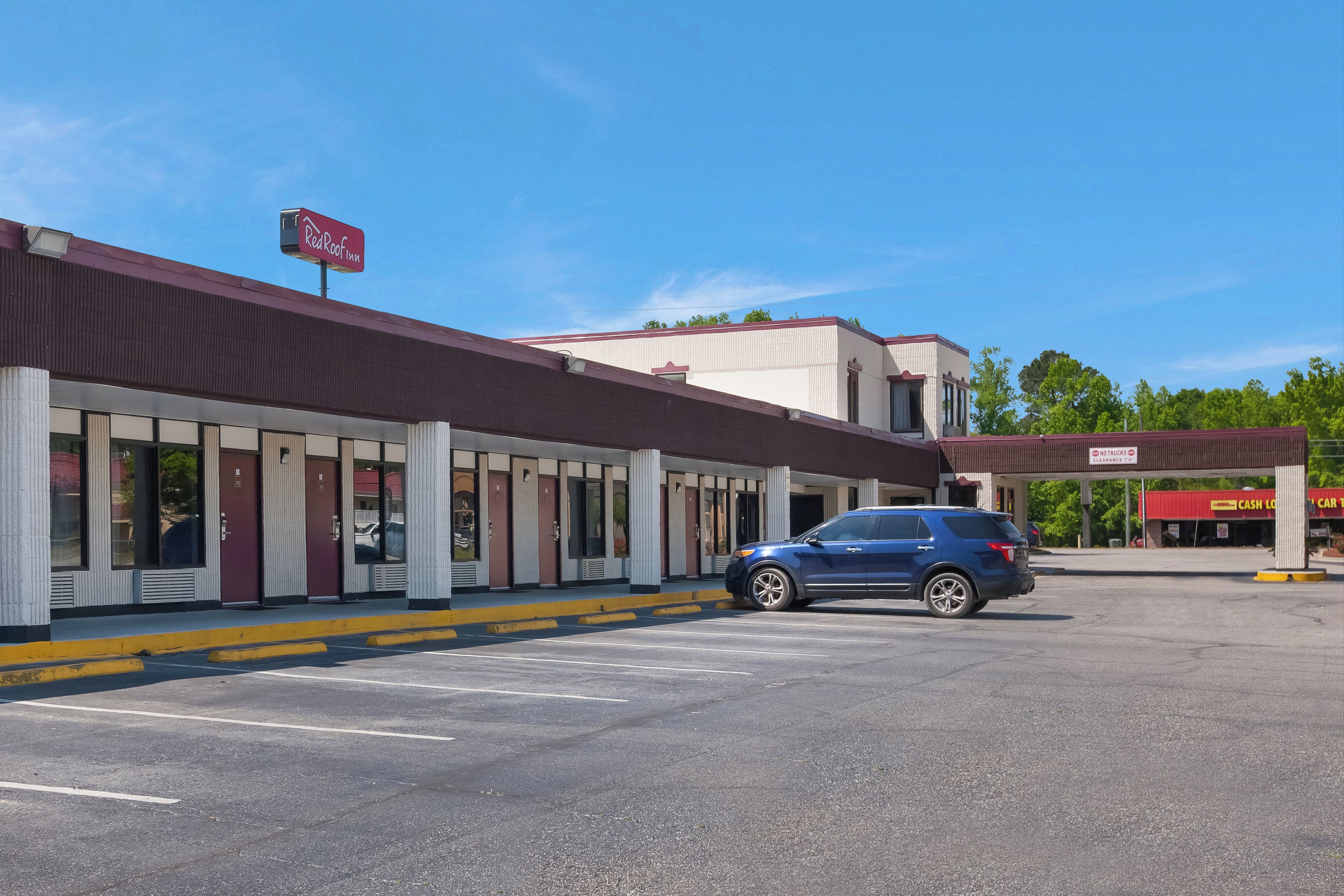 A Red Roof Inn with a parking lot and a blue SUV parked in front.