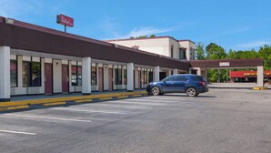 A Red Roof Inn with a parking lot and a blue SUV parked in front.