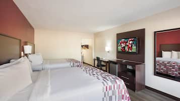 A hotel room with two beds, a desk, a television, and a mirror.