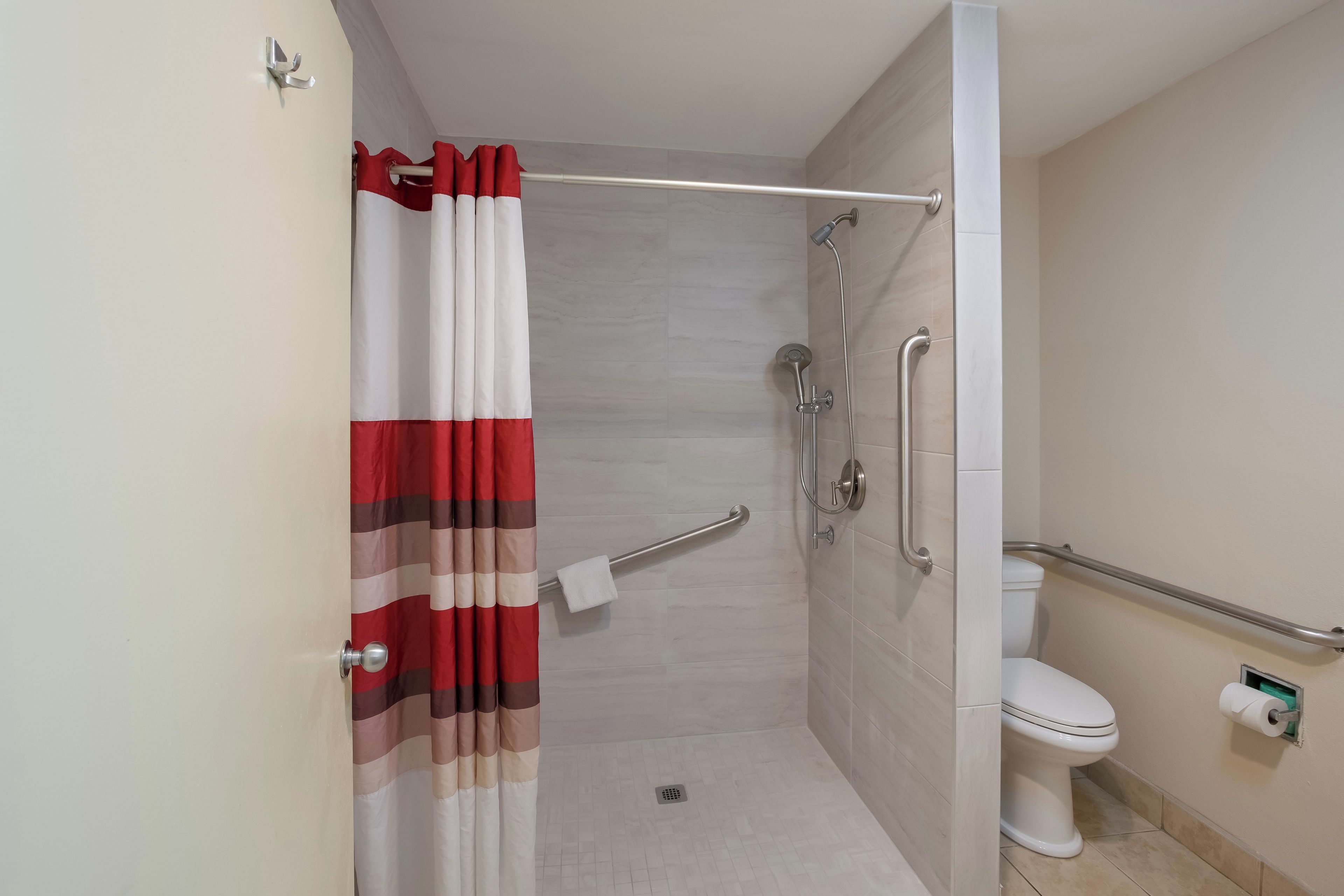 Une salle de bain équipée d’une douche, de toilettes et de barres d’appui.