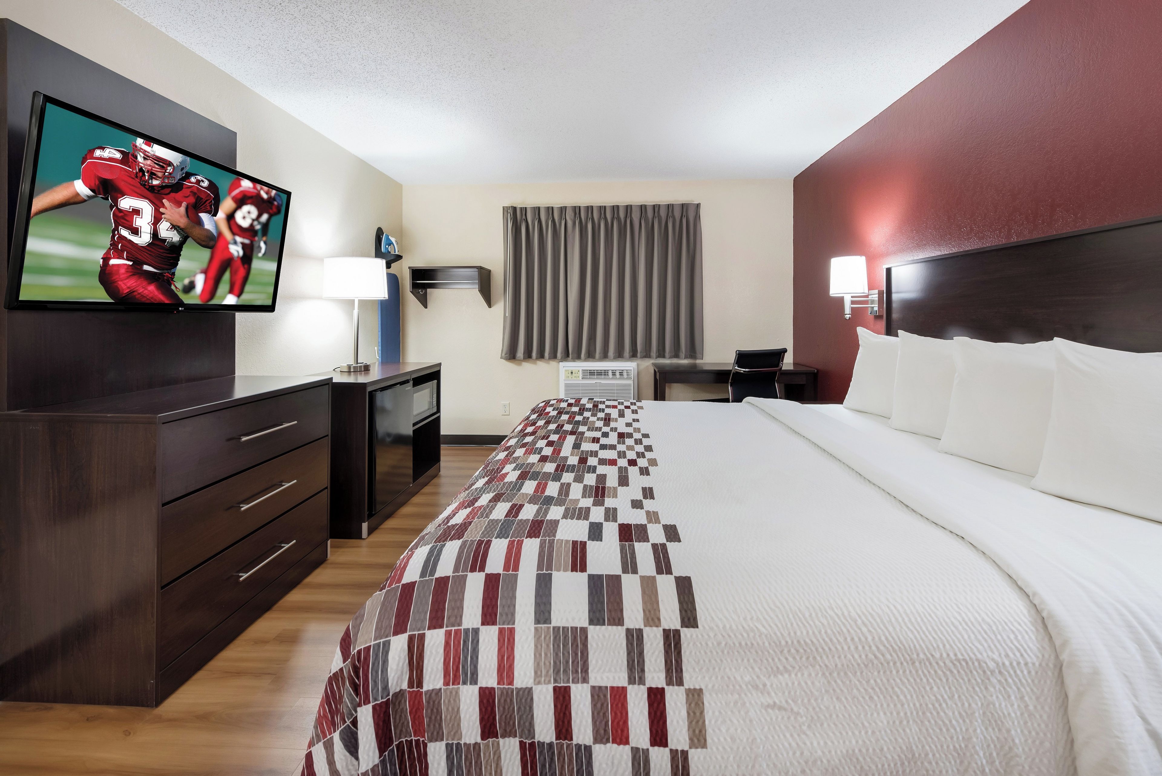 Ein Hotelzimmer mit Bett, Fernseher, Schreibtisch und Lampe.