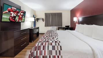 A hotel room with a bed, a TV, a desk, and a lamp.