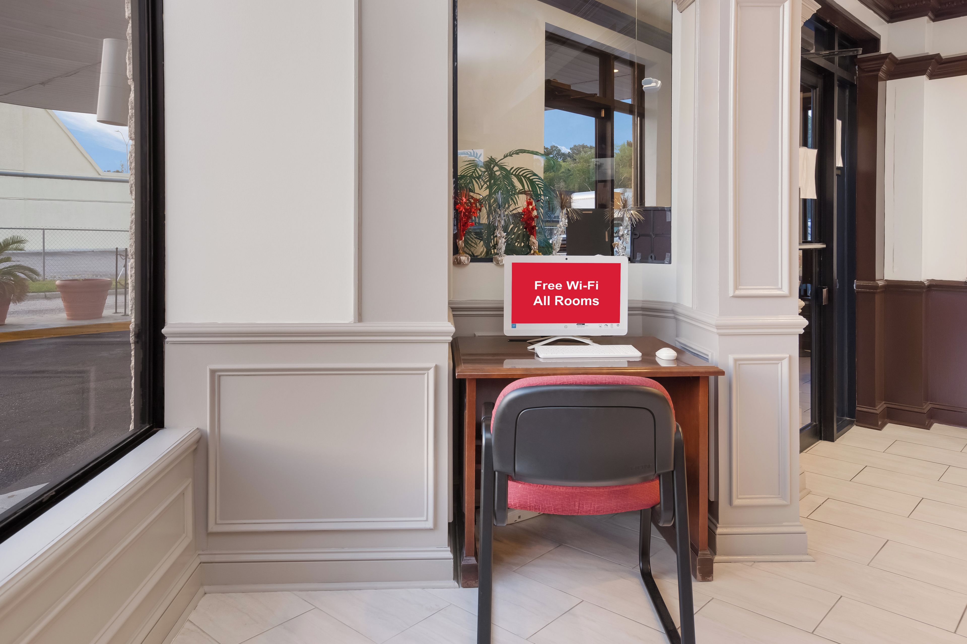 Habitación de hotel con escritorio, silla y un cartel que indica Wi-Fi gratuito en todas las habitaciones.