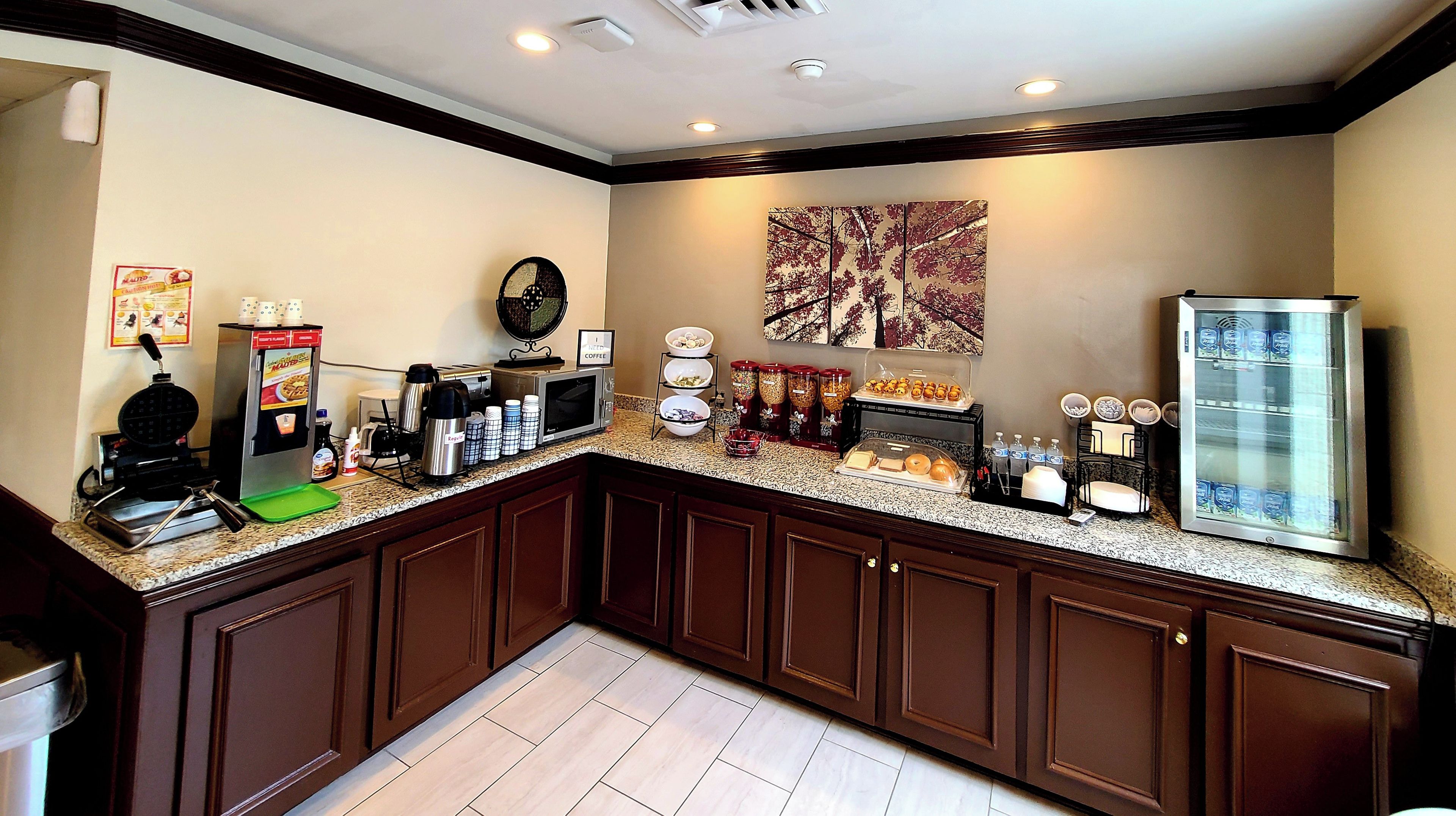 Una cocina con estación de café, plancha para gofres y refrigerador.