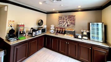 Una cocina con estación de café, plancha para gofres y refrigerador.