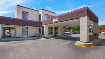 A motel with a covered parking area, a 'No Trucks Stop' sign, and a 'Clearance 7'6'' sign.