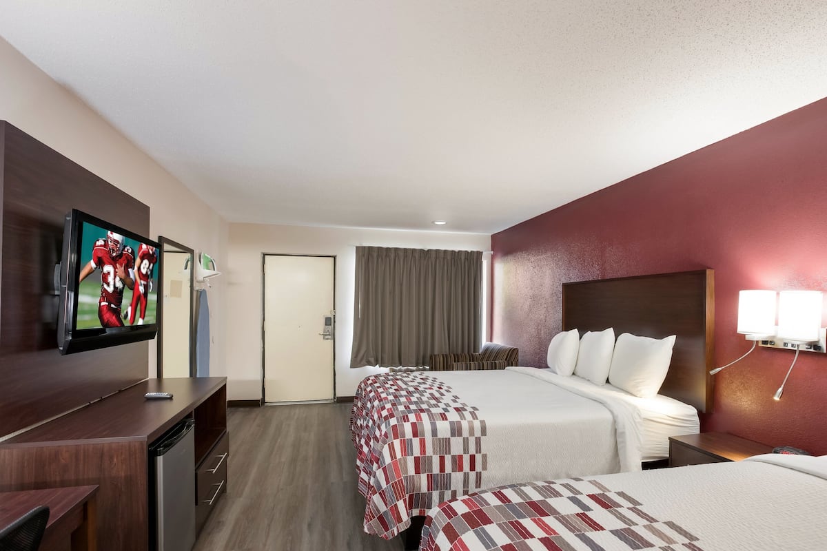 A hotel room with a bed, a TV, a desk, and a chair.