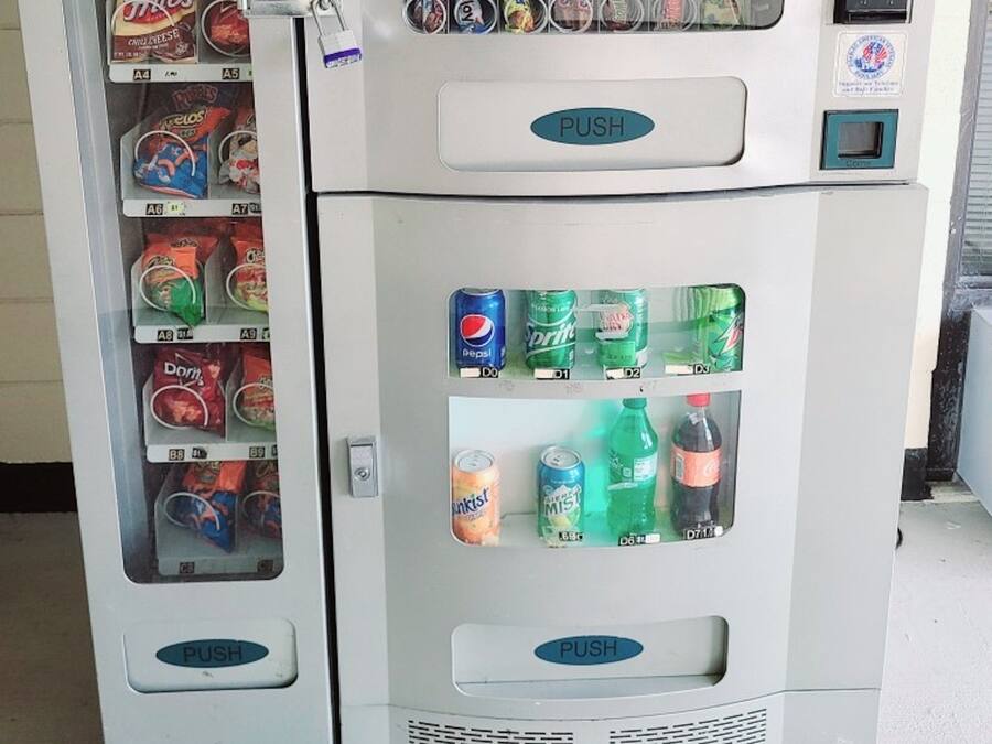 Una máquina expendedora con aperitivos y bebidas, como papas fritas, caramelos y gaseosas.