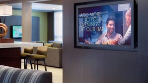A modern bar area with a TV screen displaying a message about adding more to evenings at the bar. - Courtyard by Marriott Macon (Macon)