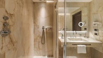 Un baño moderno con ducha de vidrio, tocador con espejo y perchero.
