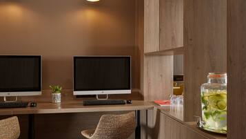 A modern workspace with two monitors, a keyboard, a mouse, a potted plant, and a large jar of iced tea.