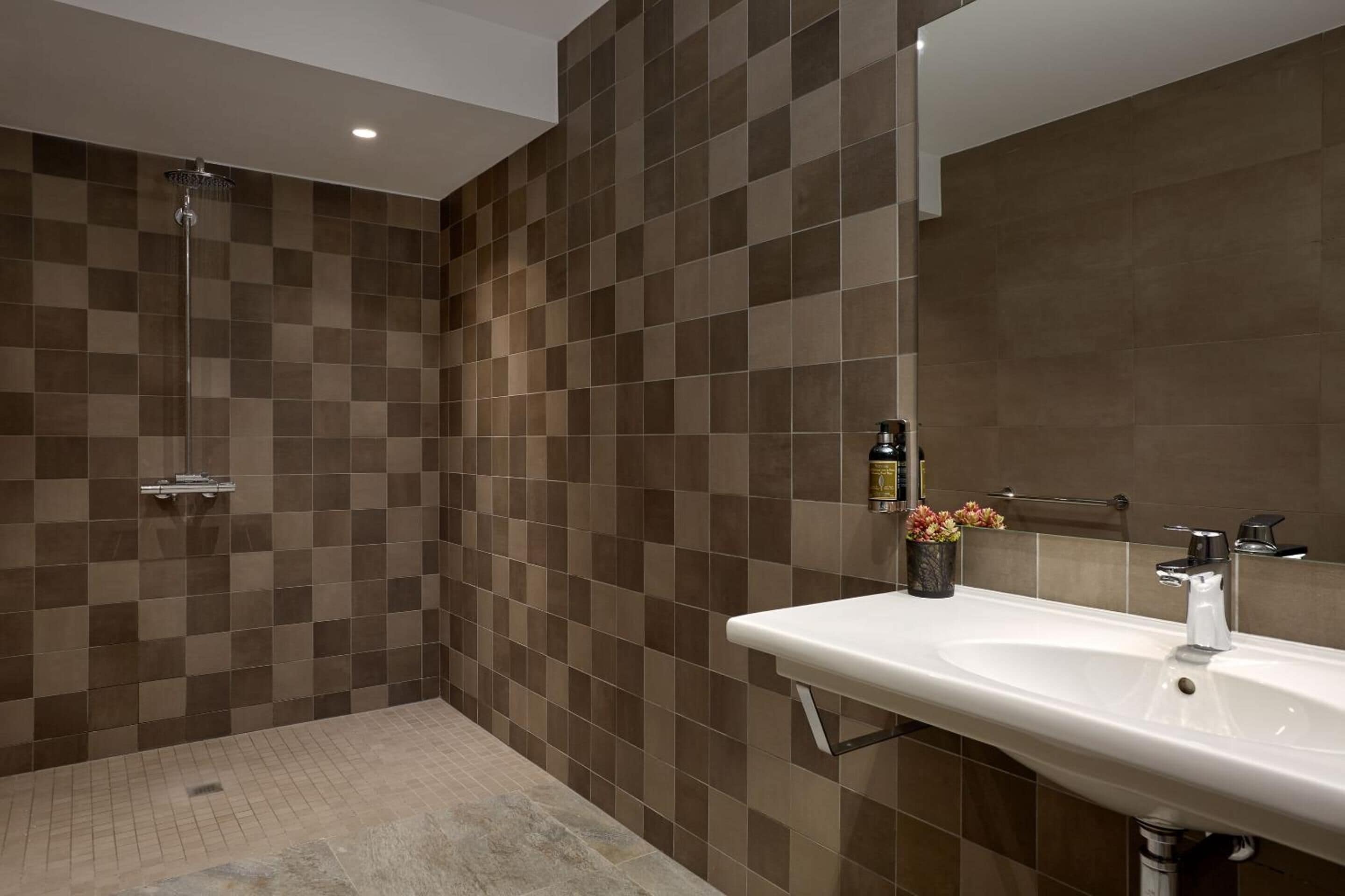 Un bany modern amb dutxa, un lavabo i un mirall.