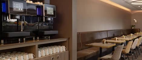 A modern restaurant with a long counter, multiple tables, and a coffee machine.