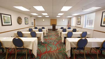 A conference room with rows of tables and chairs, a carpeted floor, and framed artwork on the walls.