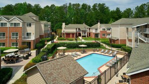 A residential building with a swimming pool, outdoor seating, and a well-maintained garden.