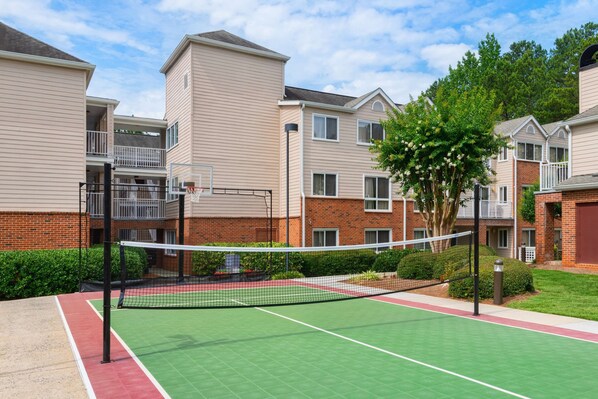 A tennis court with a net, surrounded by apartment buildings.