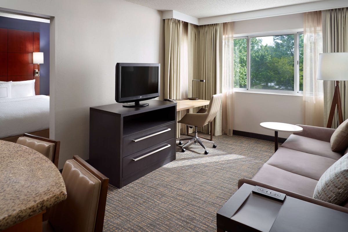 Een hotelkamer met een bed, een bureau met een computer, een bank en een bijzettafeltje.
