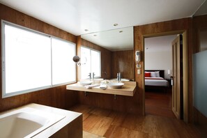Ein modernes Badezimmer mit einer großen Badewanne, zwei Waschbecken und einer begehbaren Dusche.