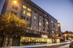 Un hotel de varios pisos con fachada moderna, amplias ventanas y una entrada bien iluminada.