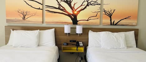 Una habitación de hotel con dos camas, una mesita de noche con lámpara y un teléfono en la pared.