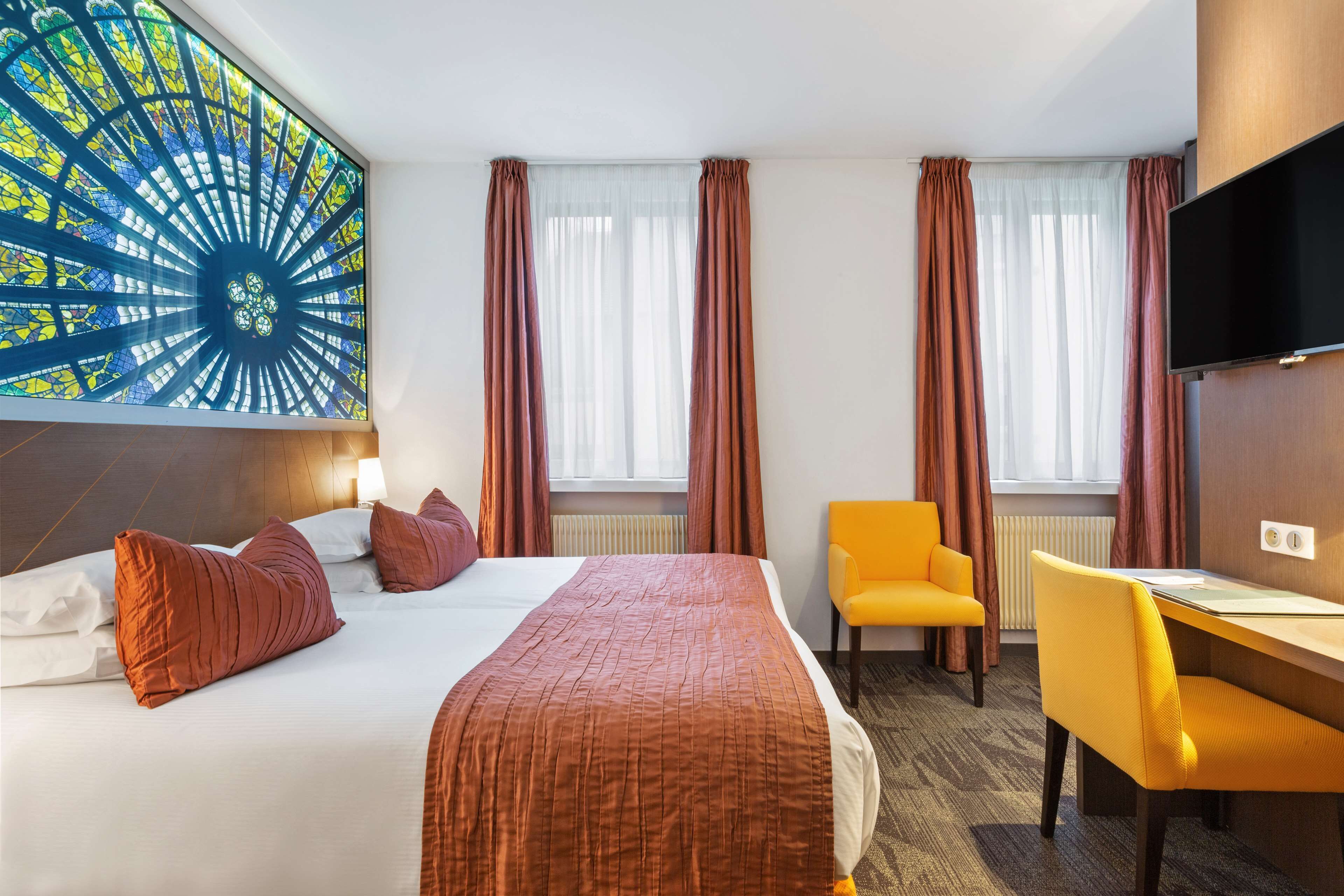 Une chambre d’hôtel avec un grand lit, un bureau, une chaise et un téléviseur.