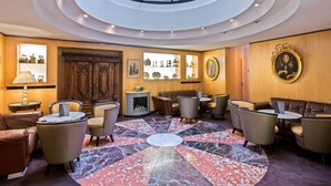 A spacious lobby with a central marble floor, seating arrangements, a fireplace, and a skylight.