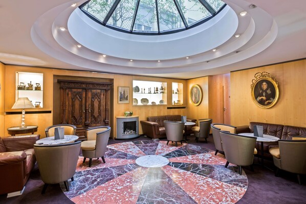 A spacious lobby with a central marble floor, seating arrangements, a fireplace, and a skylight. - Best Western Plus Monopole Metropole (Strasbourg)