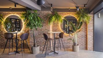 Zona de bar moderna con paredes de ladrillo, ventanas circulares y plantas en macetas.