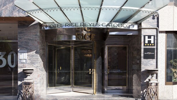 The entrance of Hotel Rice Reyes Católicos with a glass door and a metal canopy.