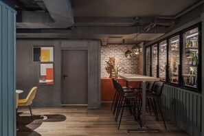 A modern bar area with a brick wall, wooden bar counter, and hanging pendant lights.