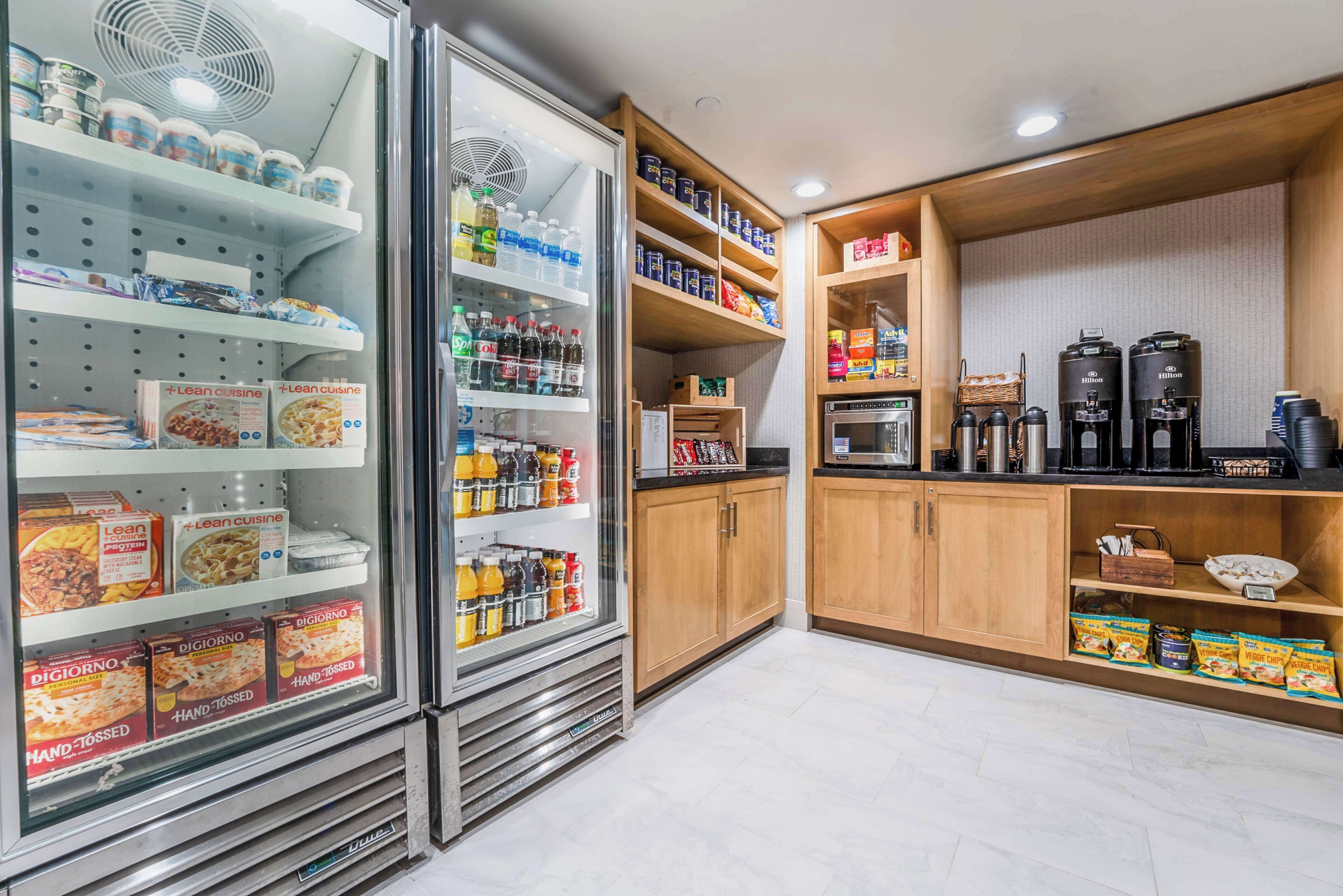 A kitchenette with a refrigerator stocked with food items, a microwave, and a coffee machine.