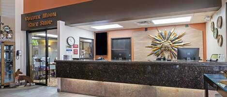 A reception desk with a sign reading "Coyote Moon Gift Shop" and a decorative wall piece.