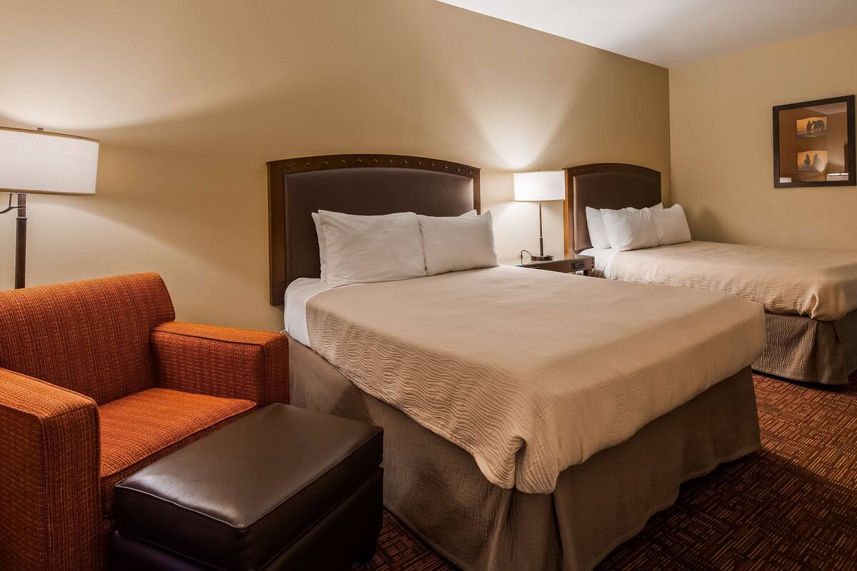 A hotel room with two beds, a sofa, and a small table.