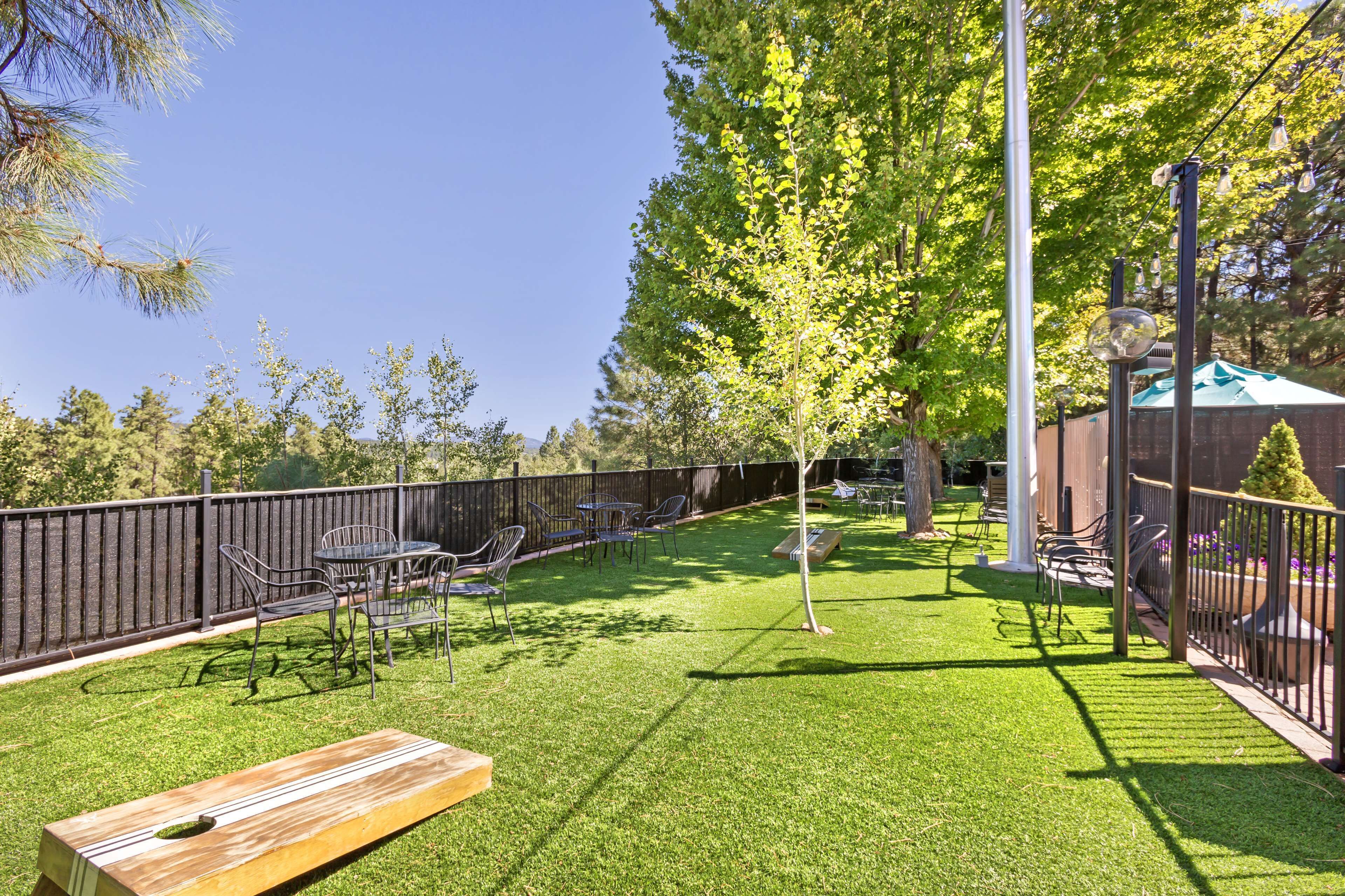 A backyard with a wooden bench, metal chairs, and a table.