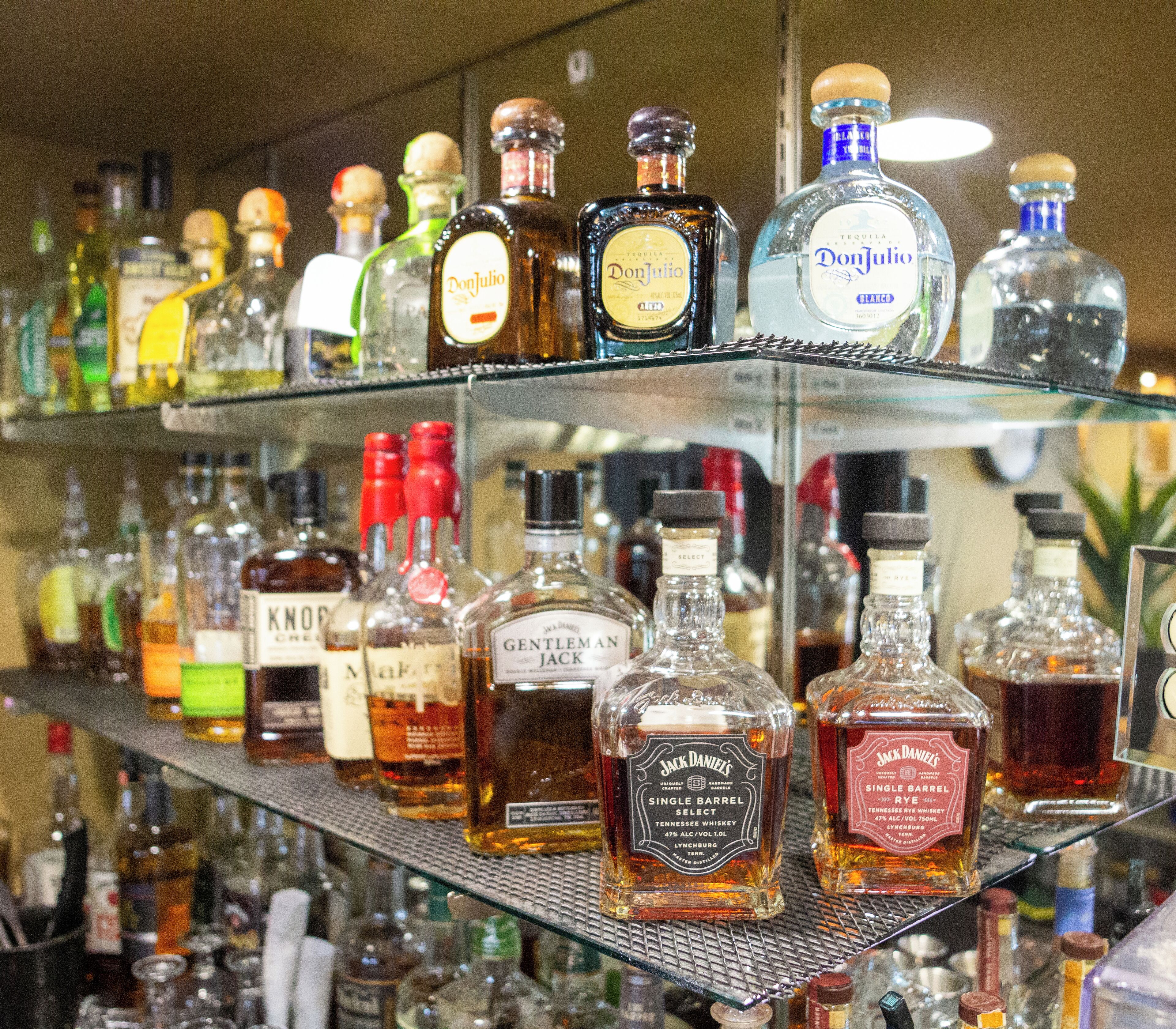 A bar with shelves stocked with various liquor bottles.