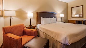 A hotel room with a bed, two bedside lamps, a chair, and a small table.