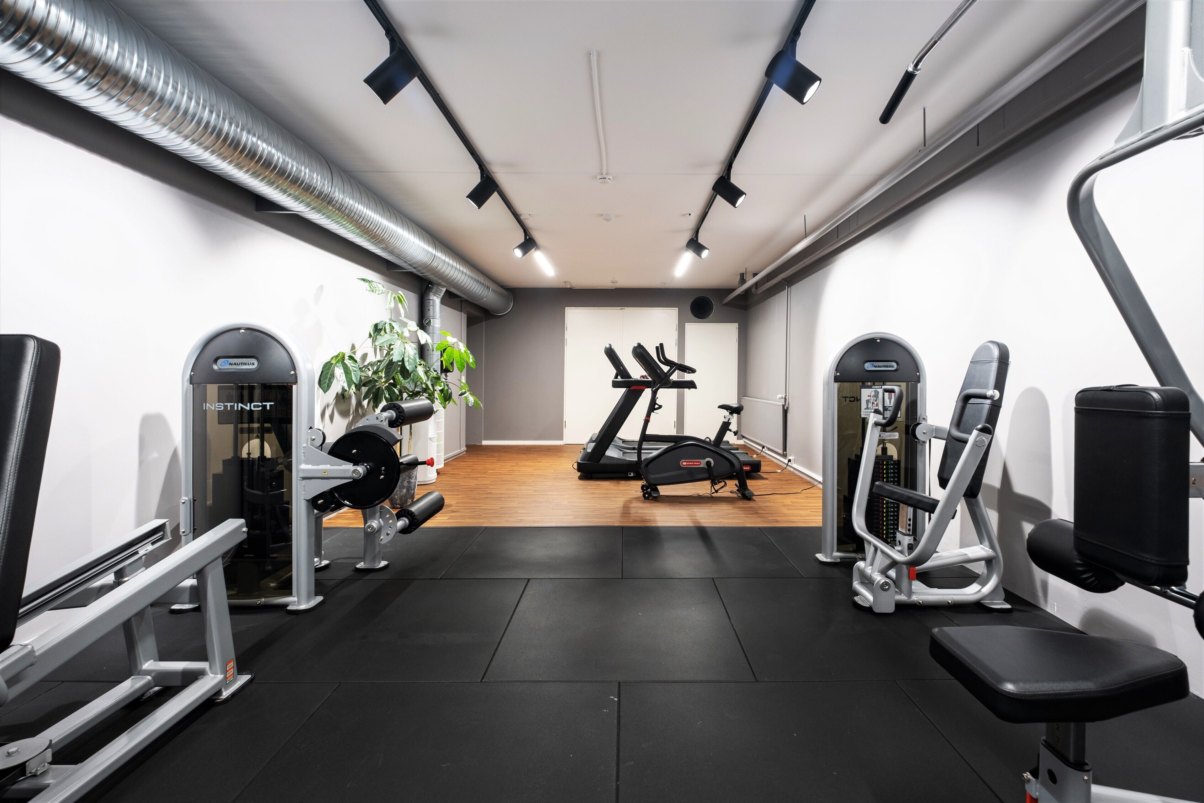 Een sportschool met trainingsapparatuur, een loopband en een rekbank.