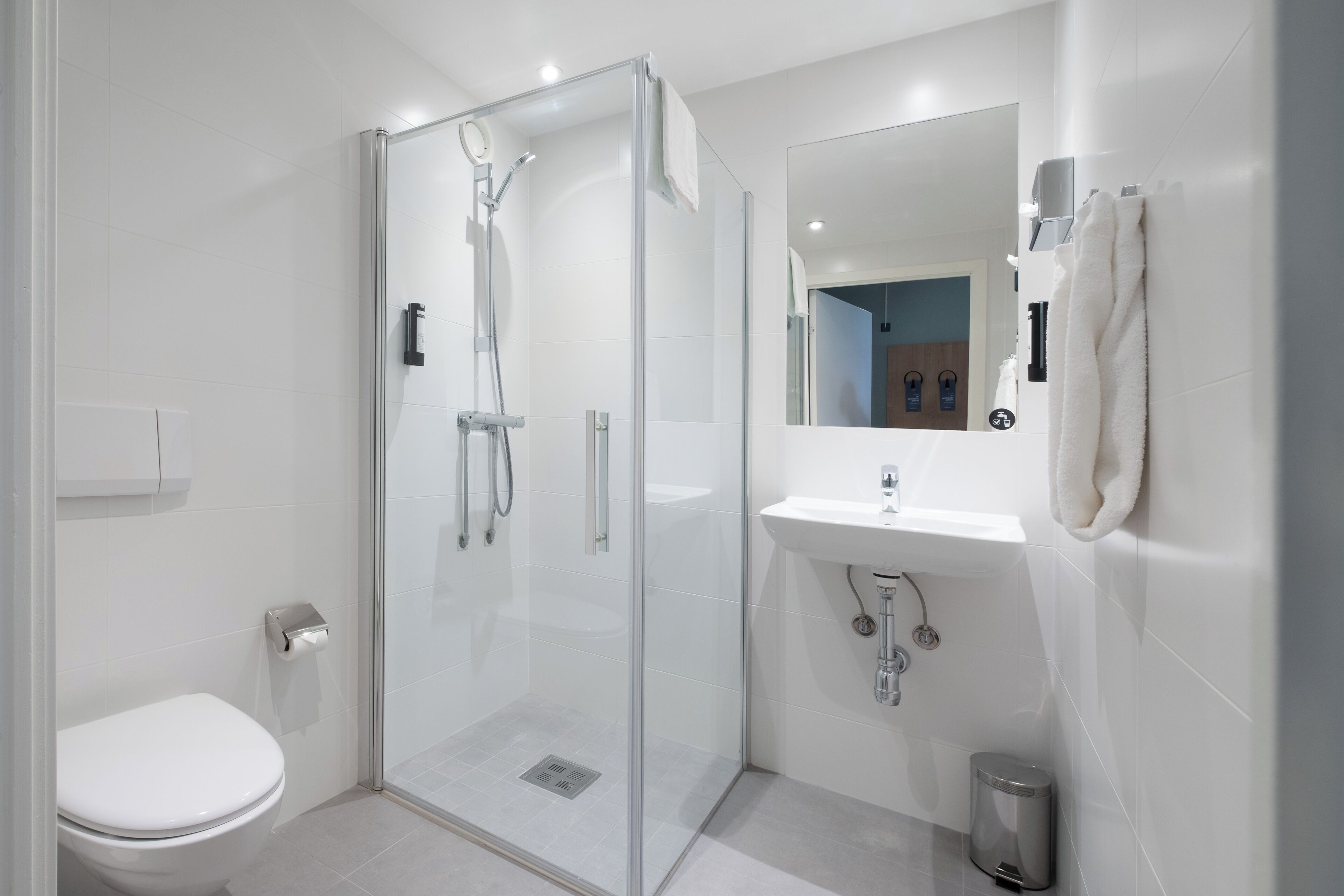Une salle de bain moderne avec une douche à parois de verre, un lavabo blanc et des toilettes.
