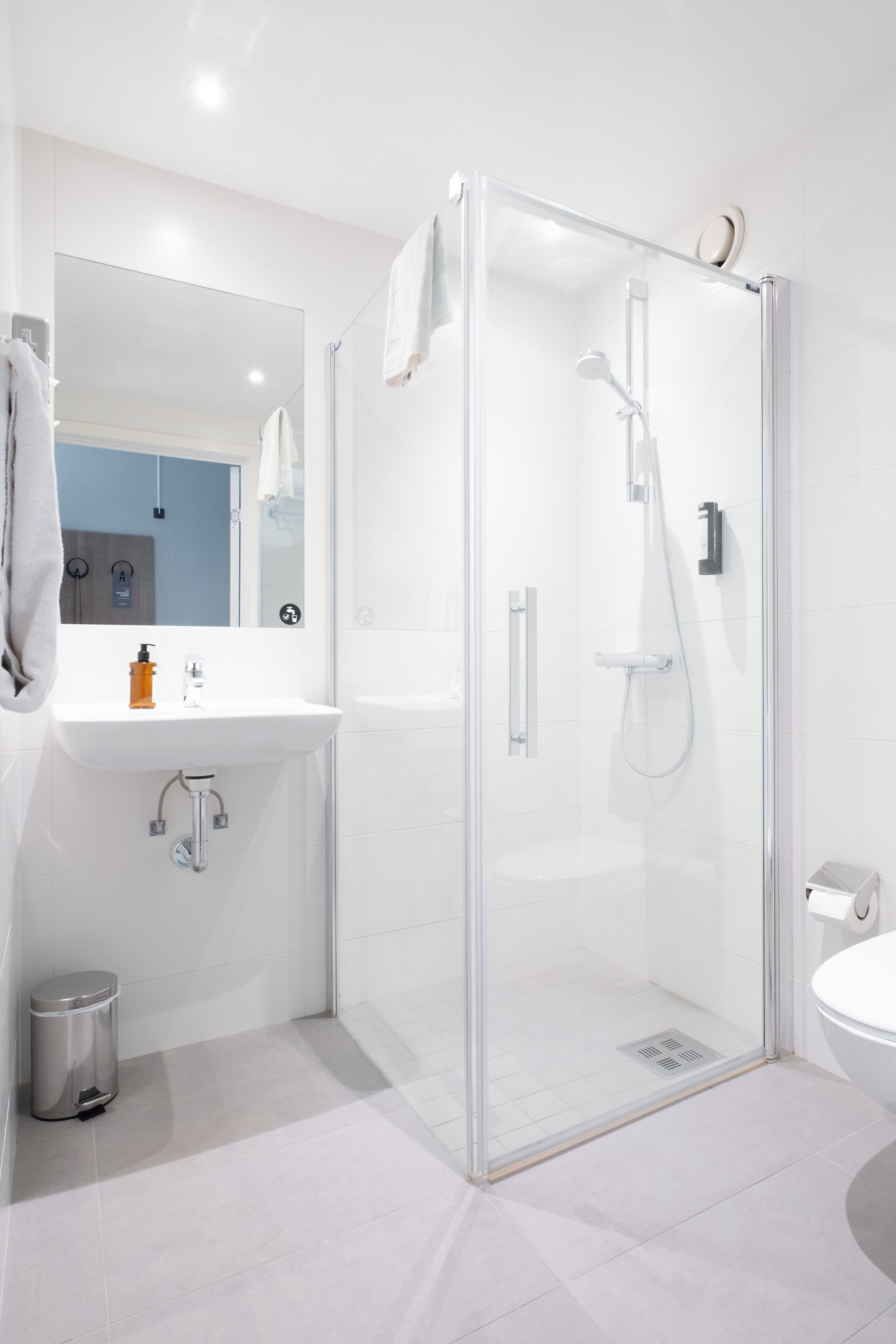 Een moderne badkamer met een glazen douchecabine, een wit wastafelmeubel en een spiegel.