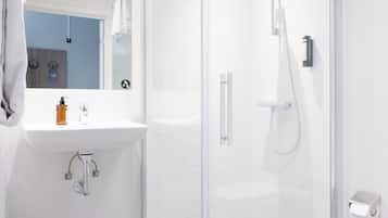 Un baño moderno con cabina de ducha de vidrio, un lavabo blanco y un espejo.