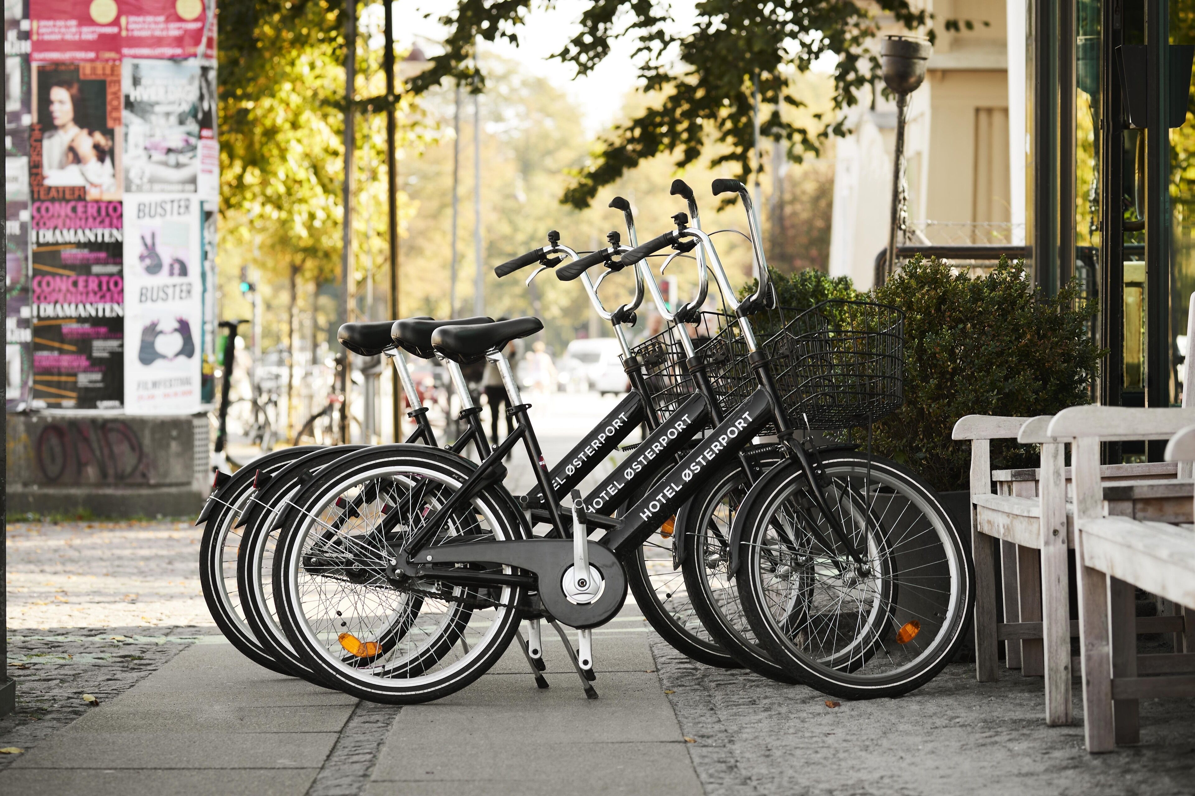 Uma fileira de bicicletas estacionadas ao lado de um banco e um edifício com uma placa que diz 'HOTEL OSTERPORT'.