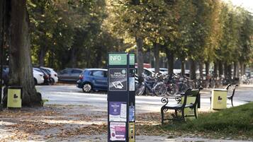 Quiosco de información sobre estacionamiento con varios letreros y un banco cerca.