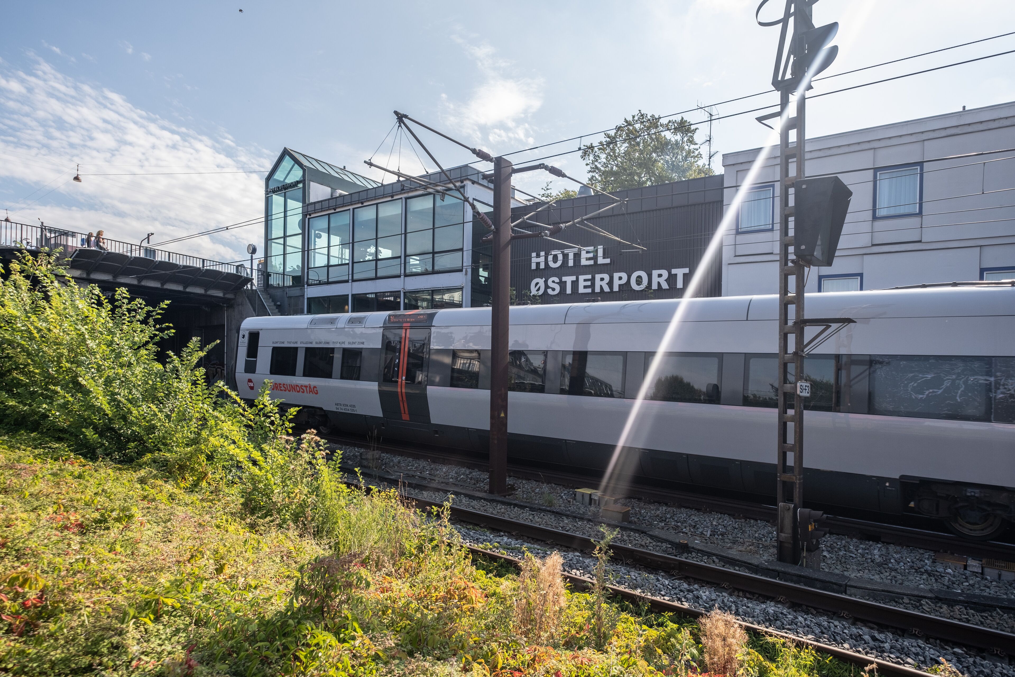 A modern train station with a glass building labeled "HOTEL OSTERPORT".